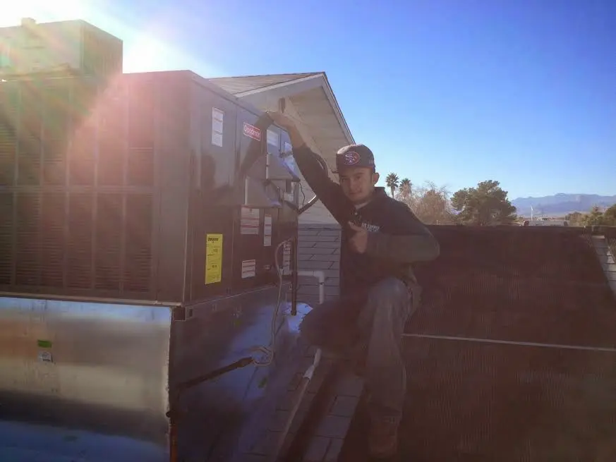 HVAC technician performing AC Tune-Up on a rooftop unit in Natick