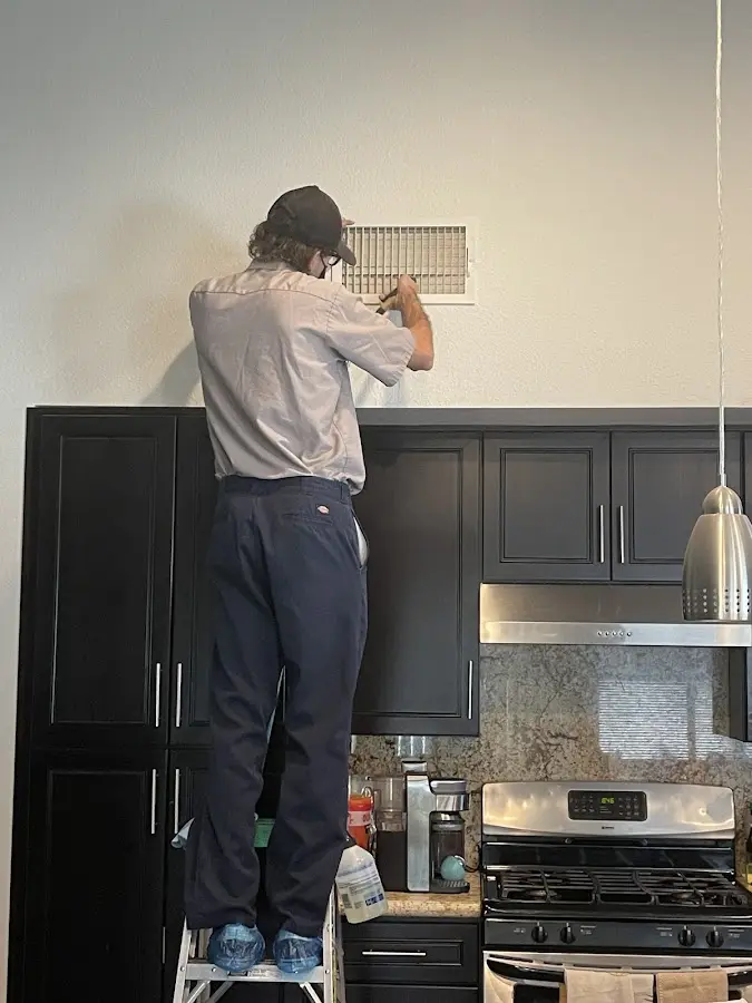 Technician inspecting an air vent during HVAC service in Natick